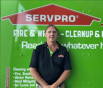 Male employee smiling in front of SERVPRO truck 