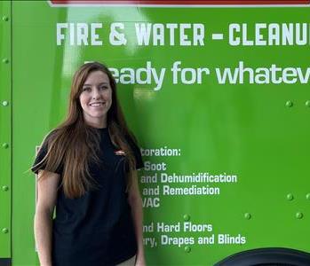 Female employee smiling in front of SERVPRO truck 